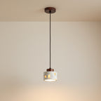 Cylindrical terrazzo pendant light with wood canopy and thin hanging cord, warm lit.