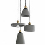 Concrete pendant light with three gray cylindrical shades and brass sockets on cords
