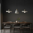 Concrete pendant light cluster with three gray shades and brass caps on hanging cords