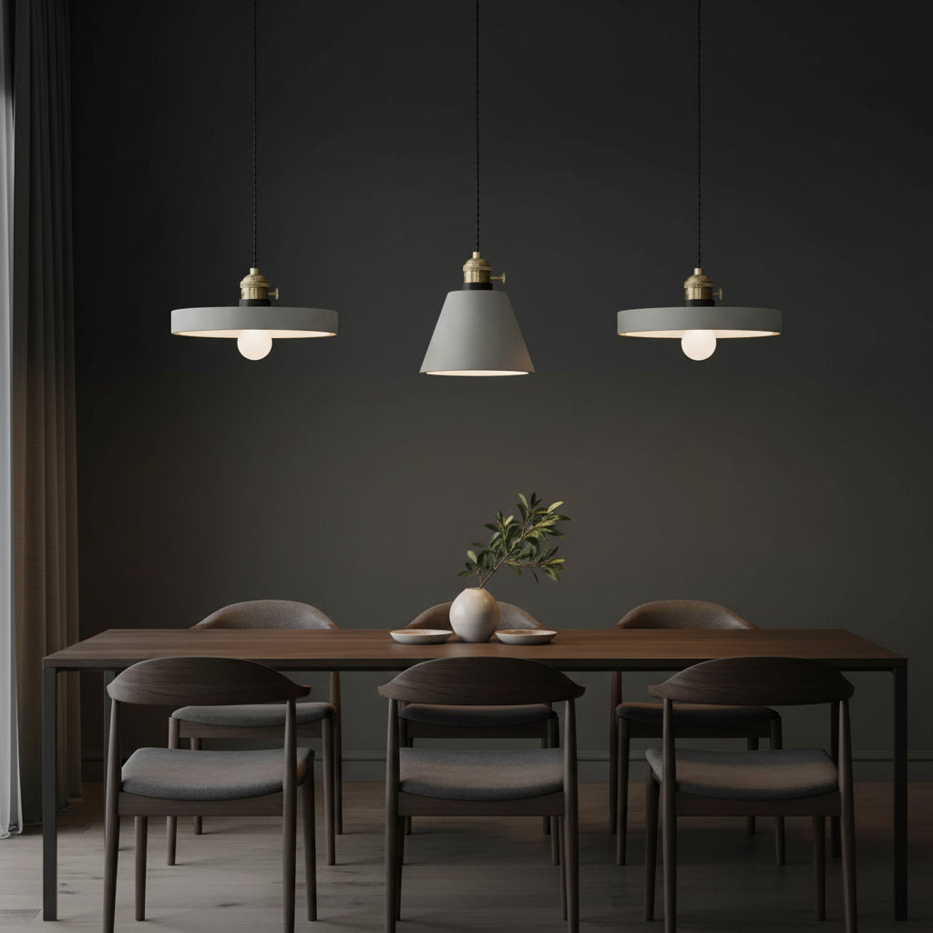 Concrete pendant light cluster with three gray shades and brass caps on hanging cords