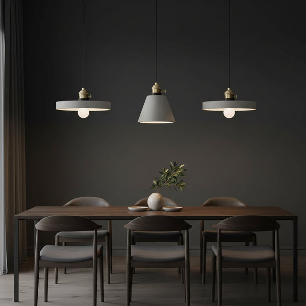 Concrete pendant light cluster with three gray shades and brass caps on hanging cords