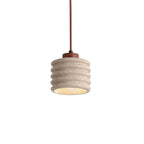 Cylindrical travertine pendant light with ribbed shade and warm glow