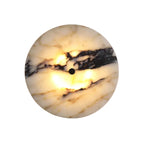 Round marble wall light with black spot, warm glow through circular stone disc