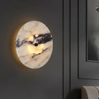 Round marble wall light with black center, warm halo glow on wall
