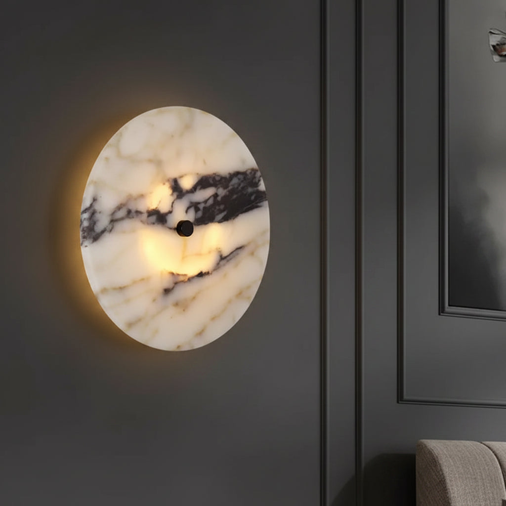 Round marble wall light with black center, warm halo glow on wall