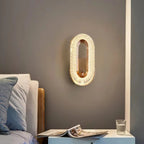 Gold oval wall sconce with textured outer rim and warm glow light source