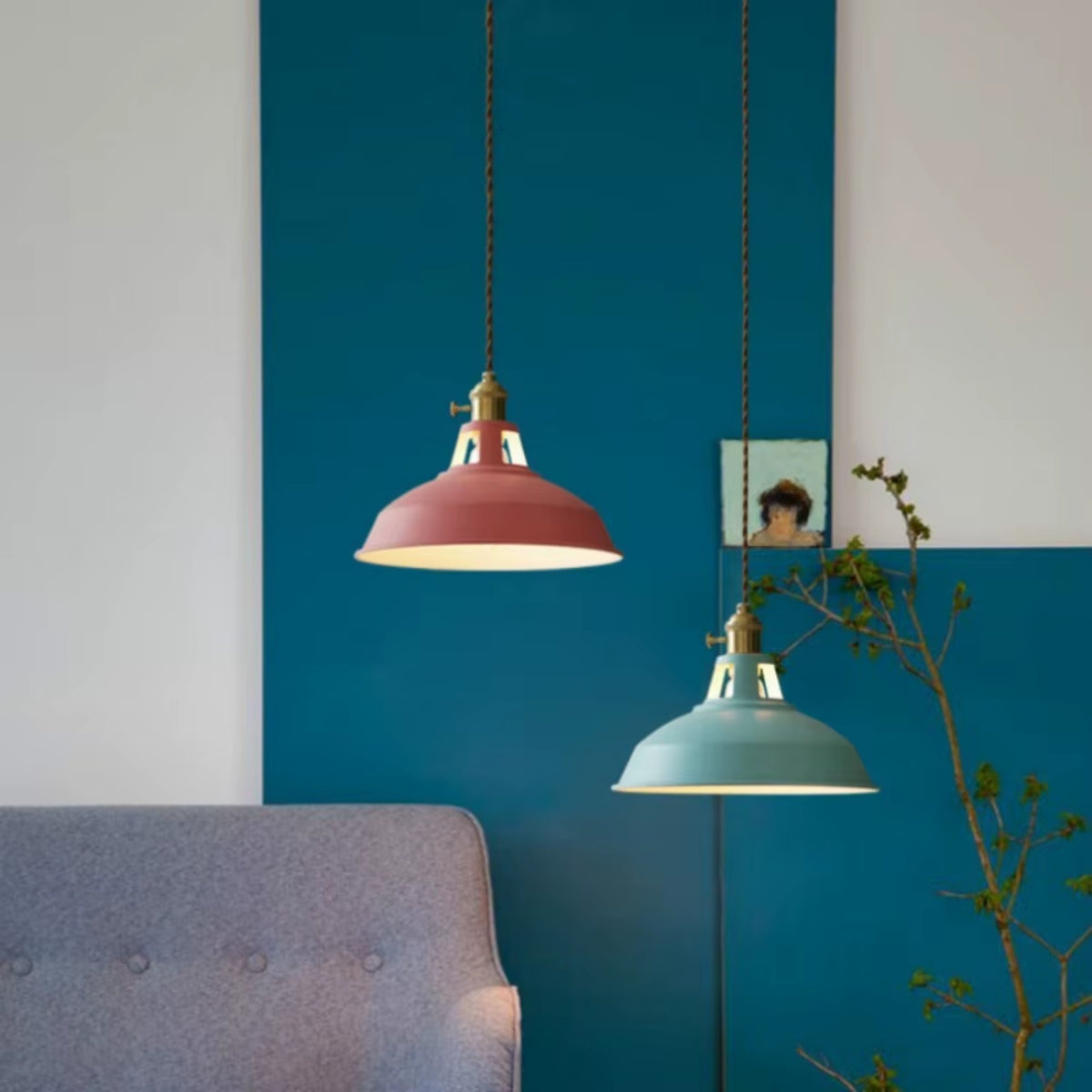 Two pendant lights with shallow pink and teal metal shades, gold chain cords