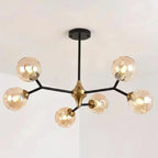 Minimalist bubble chandelier with five lit glass globes, black stems, and gold central cap