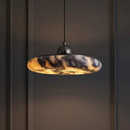 Marble pendant light against dark wall; gray-amber veined disc shade with black canopy