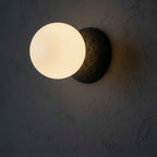 Globe wall light with frosted glass globe and textured dark concrete backplate
