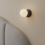 Installed globe wall light with frosted glass globe on textured concrete backplate