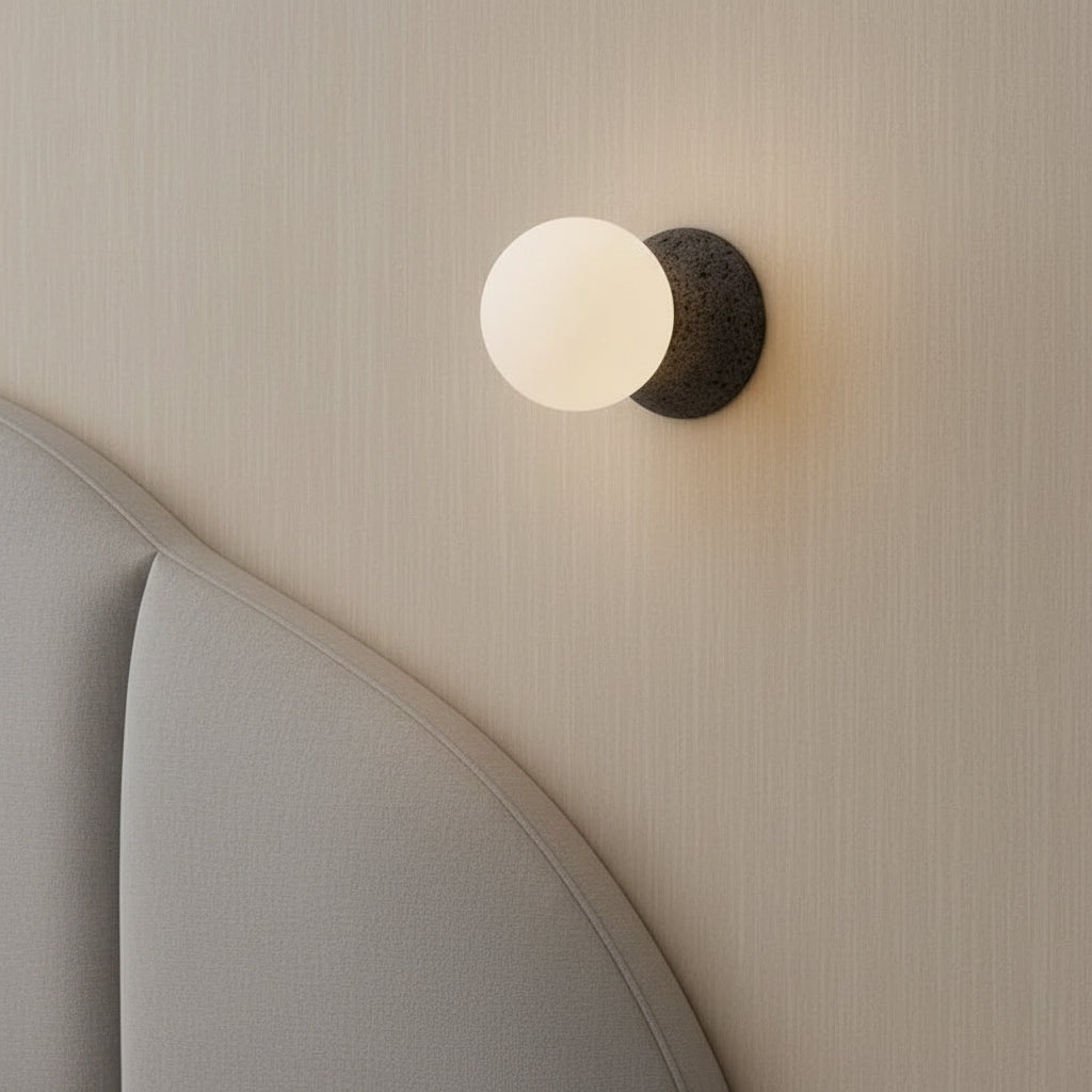Installed globe wall light with frosted glass globe on textured concrete backplate