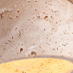 Travertine stone pendant shade with speckled texture and warm inner glow