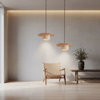 Three layered pendant lights with travertine-toned disc shades and warm glow