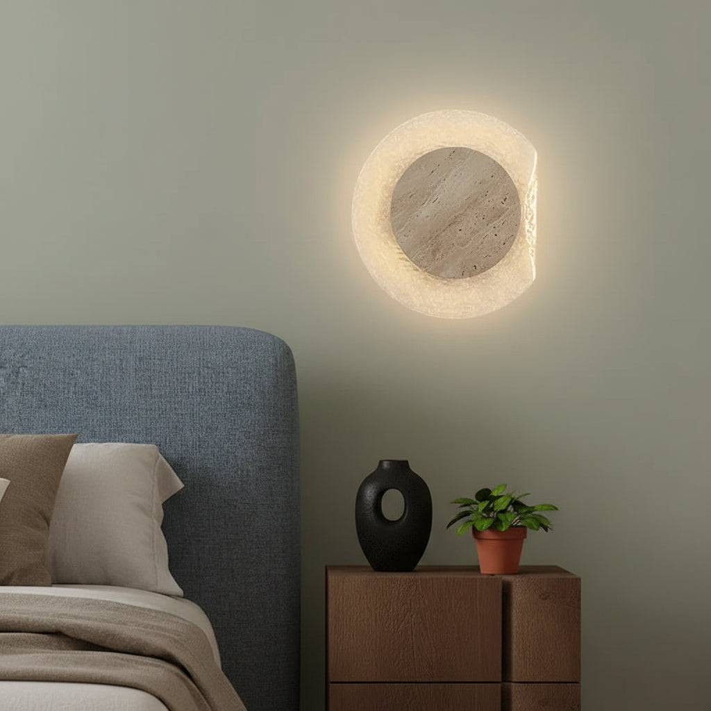 Round travertine backlit wall sconce with textured ring, warm glowing halo, and grey center