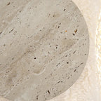 Round travertine backlit wall sconce close-up: textured tan outer ring and grey disc