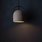 Dark speckled bell pendant light with black metal frame and warm gold interior.