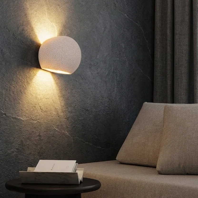 Oval concrete wall light with globe shade, warm upward glow on wall