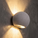 Oval concrete wall light with textured globe shade, warm glow from oval opening