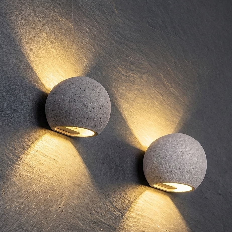 Pair of oval concrete wall lights with textured globe shades, warm beams on wall