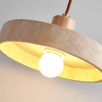 Close-up of round travertine pendant shade glowing warm under a wood canopy