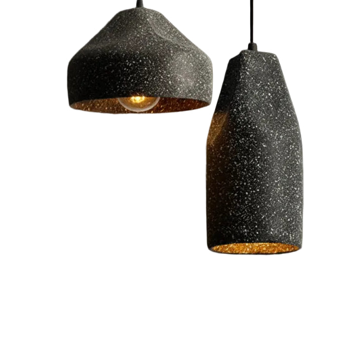 Two speckled black concrete cylinder pendant lights with warm amber light