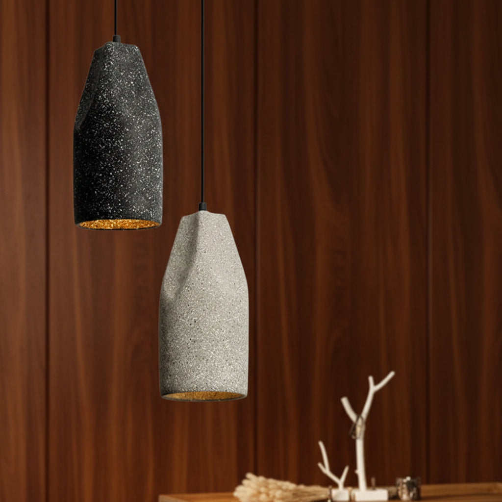 Speckled black concrete cylinder pendant light with warm amber glow on underside