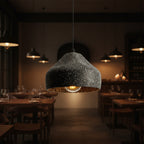 Speckled black concrete cylinder pendant light hanging over dining area