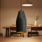 Speckled black concrete cylinder pendant light with amber-lit interior
