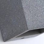 Concrete cube wall light close-up, speckled concrete texture and corner edge