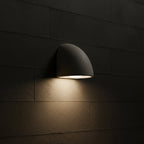 Half-dome wall light mounted on block wall, gray shade with warm light