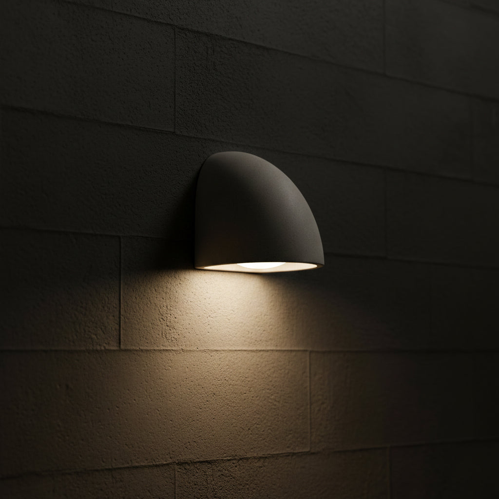 Half-dome wall light mounted on block wall, gray shade with warm light